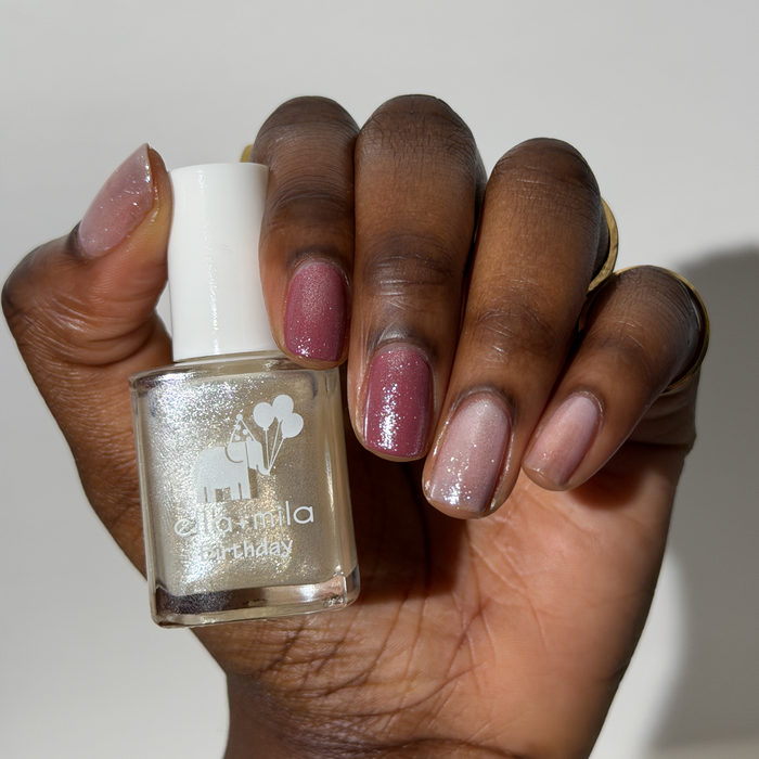 12th Era pearly white shimmer nail polish on a deep skin tone, hand holding the bottle