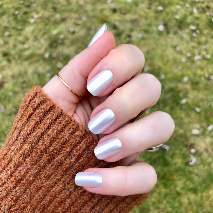 Atlas - Press-On | Short | Squoval showing hand wearing short squoval pearly white press-on nails outdoors on grass background