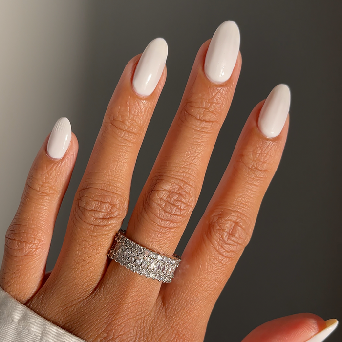 Boss milky white nail polish manicure on a medium skin tone with a rhinestone ring
