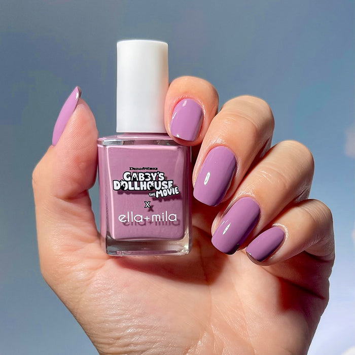 Gabby's Dollhouse DJ Catnip Party Time lilac nail polish manicure on a medium skin tone, holding the bottle