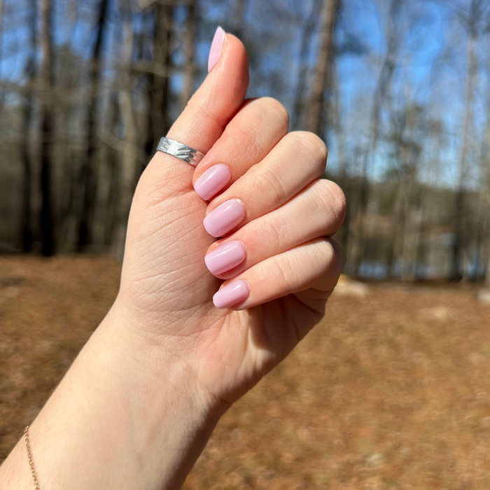 Lavender Stems - Press-On | Extra Short | Squoval showing hand with soft milky lavender false nails in extra short squoval shape outdoors