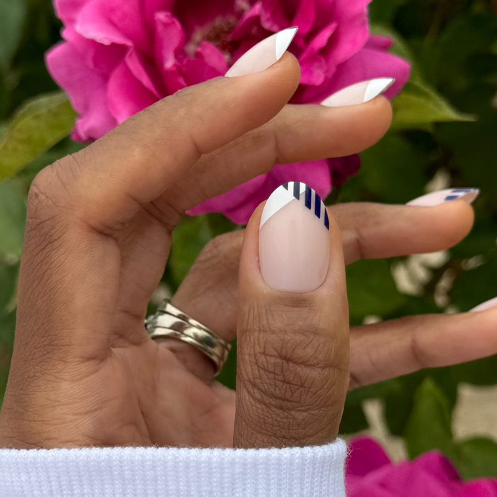 Nautical Split French - Press-On | Medium | Oval showing navy striped french manicure on oval false nails with pink flowers background