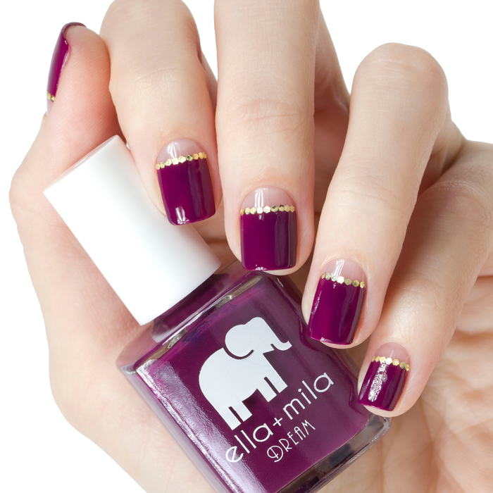 Rising Violet violet nail polish with gold glitter tip accent nails, holding the bottle