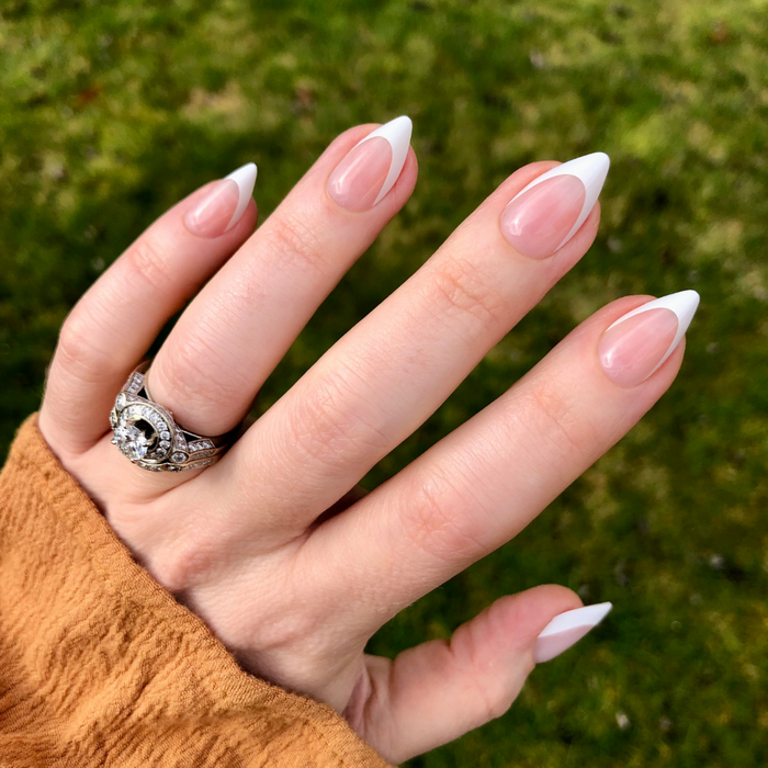 Sharp French - Press-On | Medium | Stiletto showing hand with pointed stiletto false nails and classic french tip manicure outdoors