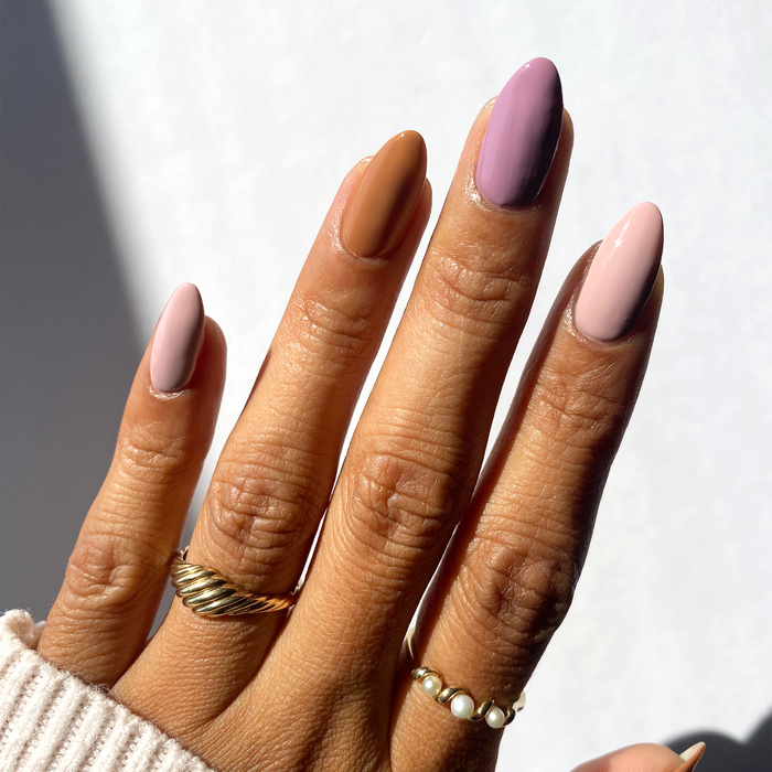 Stay Cozy mauve, taupe and nude mix-and-match manicure with gold rings in sunlight