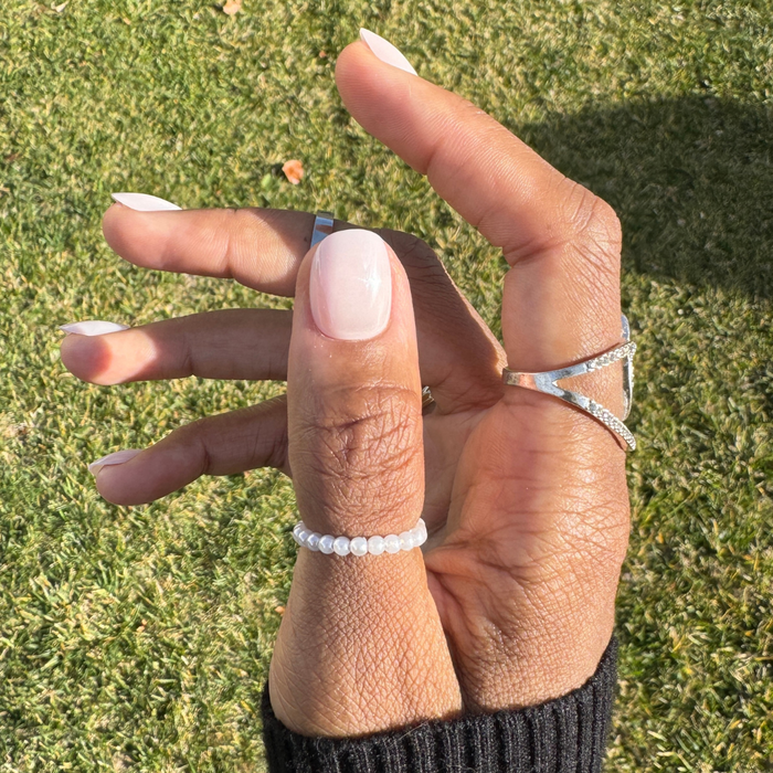 Sugar Glaze - Press-On | Extra Short | Round showing shiny sheer white nails with chrome glaze on hand with silver and pearl rings