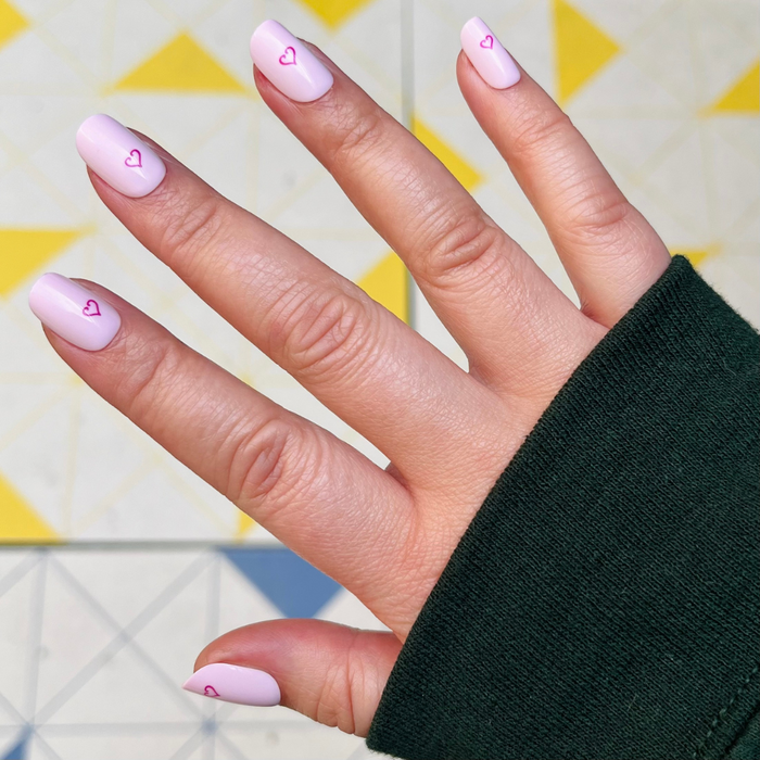 Tiny Heart Tattoo - Press-On | Short | Squoval showing hand with pale pink short squoval nails featuring small outlined heart design