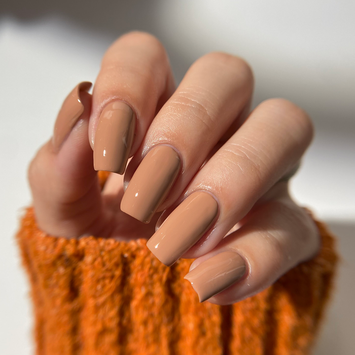 11th Hour mocha brown nail polish manicure on a light skin tone with an orange sweater