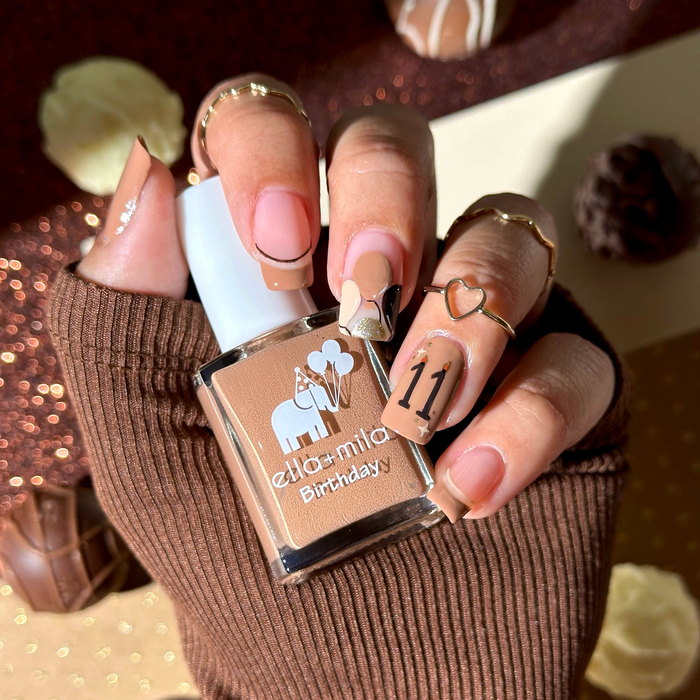 11th Hour mocha brown nail polish manicure holding the bottle with a brown sweater
