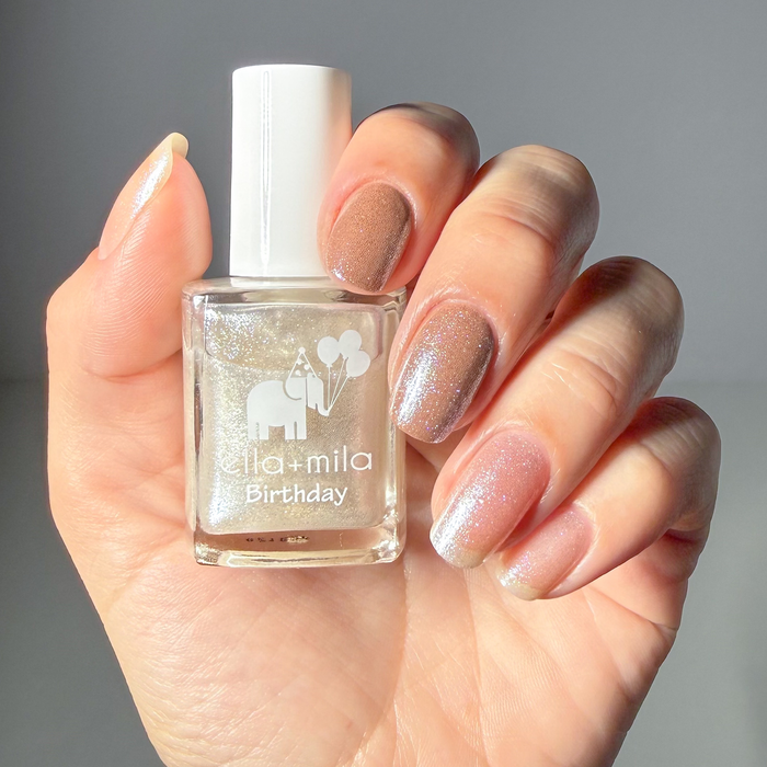 12th Era pearly white shimmer nail polish manicure on a light skin tone, holding the bottle