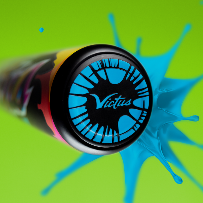 A close-up of the Victus 2024 Vibe (-10) 2 3/4" USSSA Baseball Bat (VSBVIB10) end cap, featuring a black and blue design, set against a bright green background with a vibrant blue paint splash effect.