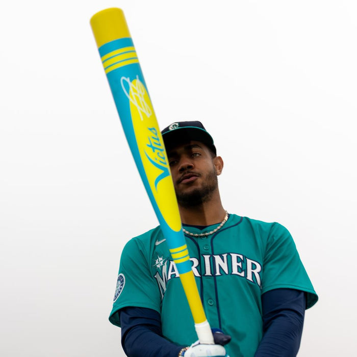 A man holding a 2025 Victus Vibe Pro-Crayon Julio Rodriguez (-5) 2 3/4" USSSA Baseball Bat (VSBVIB5C-JR), a one-piece aluminum bat with a vibration reducing knob.