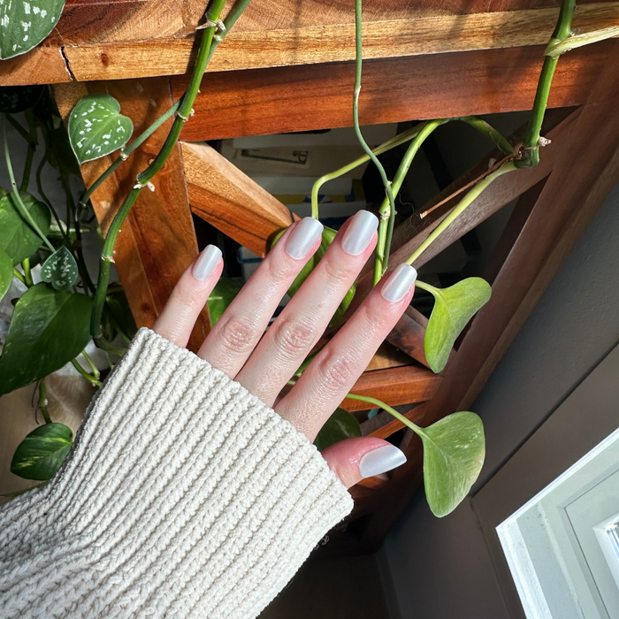 Atlas - Press-On | Short | Squoval showing natural light on hand wearing short pearly white squoval press-on nails indoors near plants