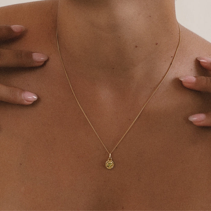 Gold necklace with a pendant on a person's neck