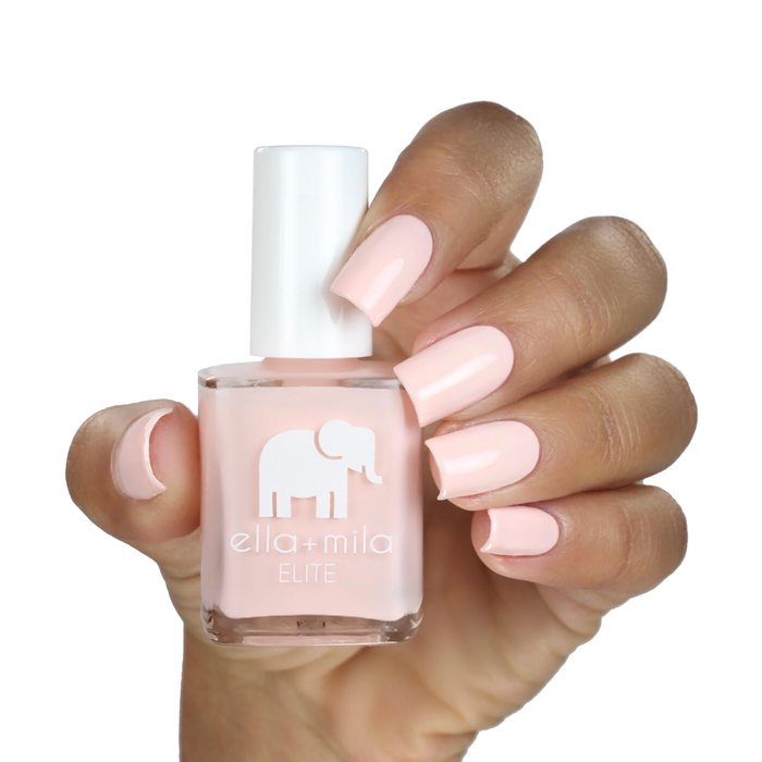 Barefoot pale nude pink nail polish on a medium skin tone, hand holding the bottle