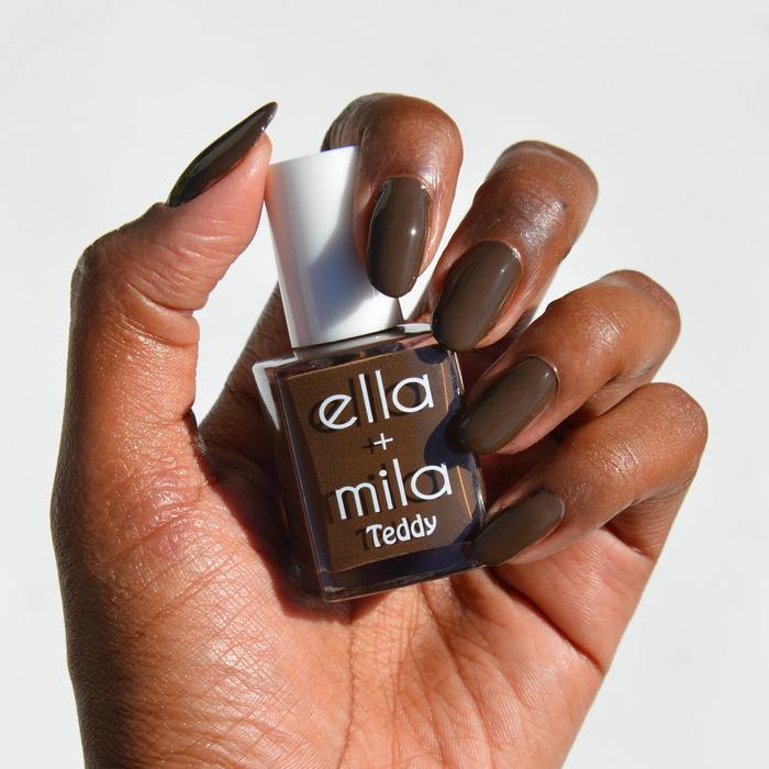 Bear with Me deep espresso brown nail polish on a deep skin tone, hand holding the bottle