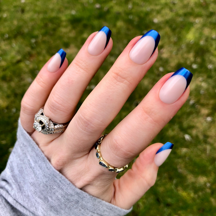 Blue Metallic French - Press-On | Medium | Coffin showing hand with medium coffin press-on nails and metallic blue tips outdoors