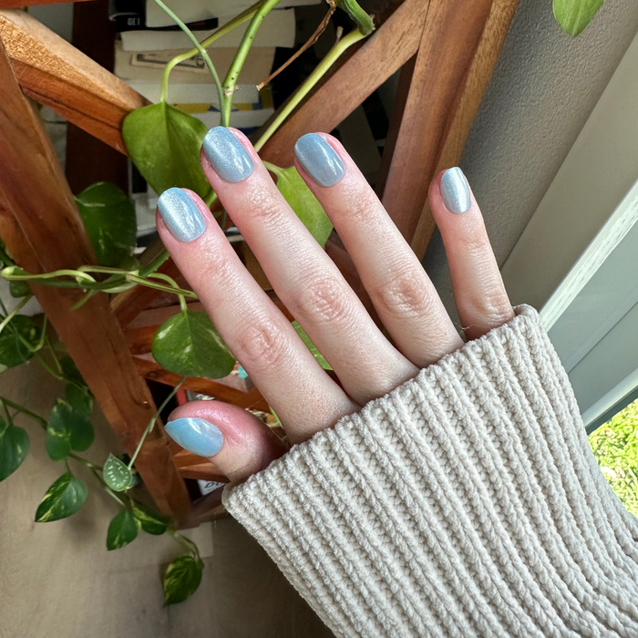 Blue Velvet - Press-On | Extra Short | Round showing hand with extra short round blue velvet press-on nails indoors near plants