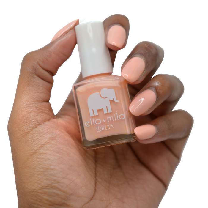 Bubble Trouble peachy bubblegum pink nail polish on a deep skin tone, hand holding the bottle