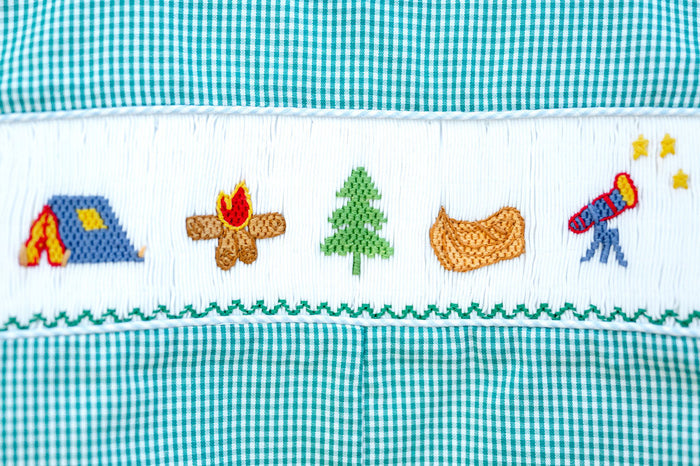Close-up of smocked camping embroidery detail on Ruth and Ralph teal gingham Jon Jon, featuring tent, campfire, and canoe