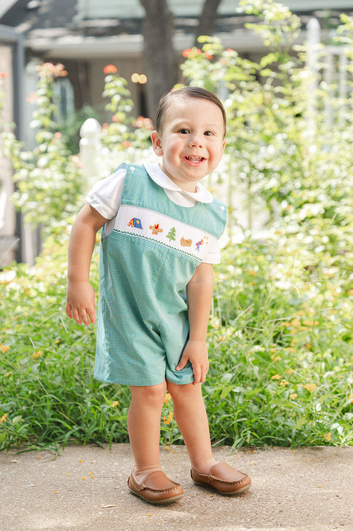 Toddler standing outdoors wearing Smocked Camping Jon Jon by Ruth and Ralph, teal gingham