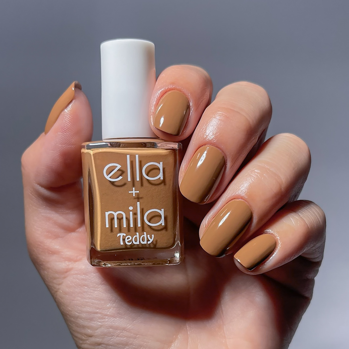 Caramel Cub medium chestnut brown nail polish manicure on a light skin tone, holding the bottle