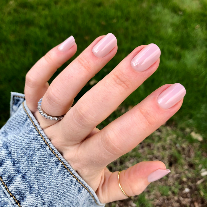 CDJ Syrup Gradient - Press-On | Short | Squoval showing hand with short squoval nails in soft neutral grey-beige press-on manicure outdoors