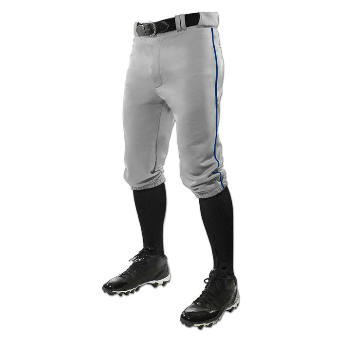 The lower half of a person is shown wearing Champro Sports Adult Triple Crown Knicker Baseball Pants with Piping (BP101A) in gray, paired with a black belt, black knee-high socks, and black cleats.