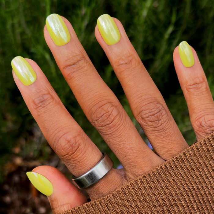 Citrus Chrome - Press-On | Short | Round showing hand with shiny bright yellow chrome short round press-on manicure outdoors