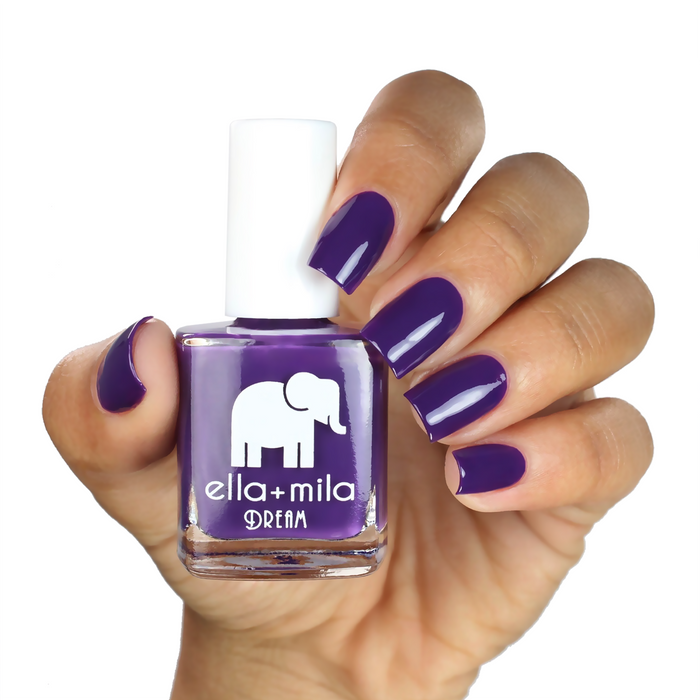 Date Night dark purple-red nail polish on a medium skin tone, hand holding the bottle