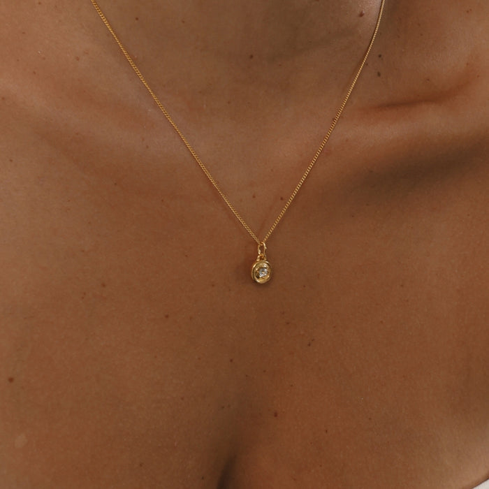 Gold necklace with a small pendant on a person's neck