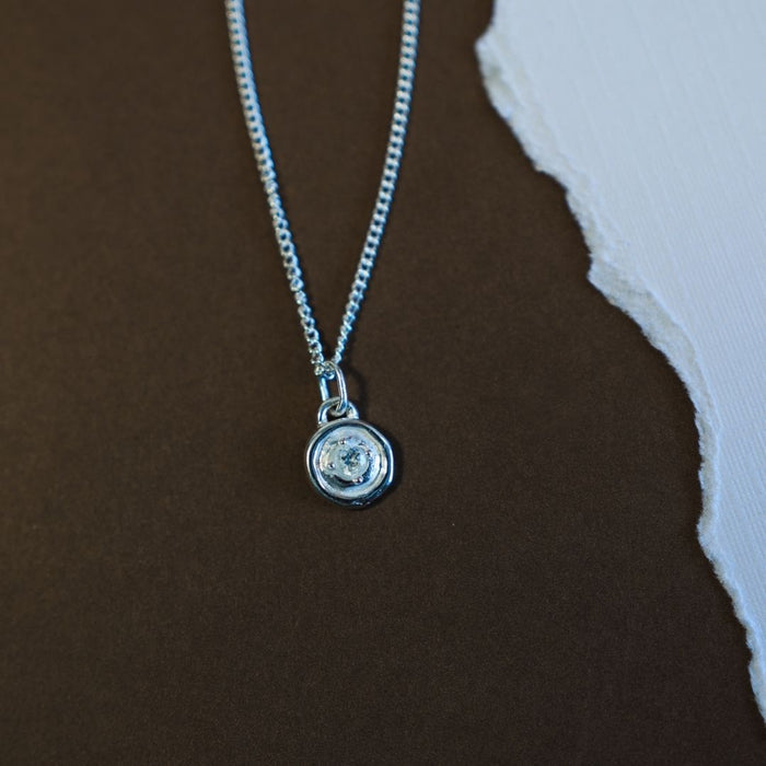Silver necklace with a pendant on a brown surface