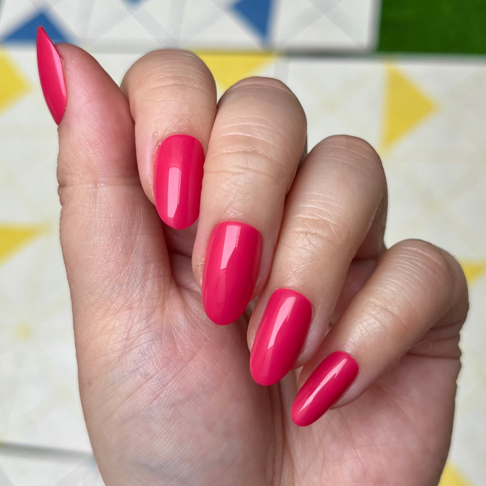 Diner Date - Press-On | Medium | Oval showing hand with medium oval hot pink press-on nails against colorful patterned background