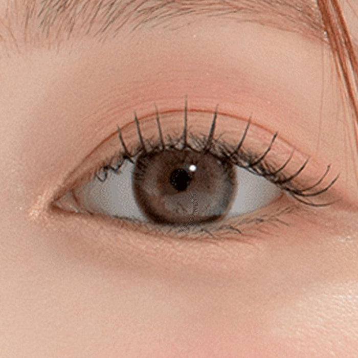 Macro shot of an eye wearing the DooNoon Bono Cheese Grey prescription colour contact lens, showing the multi-colored detail and natural effect on dark brown eyes.