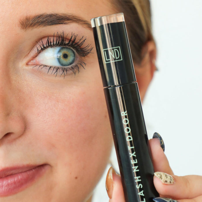 Woman holding a black eyelash extension product with 'LND' branding.