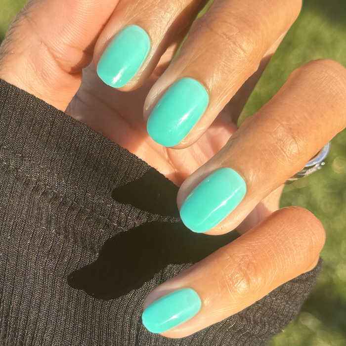 Fresh Aqua - Press-On | Short | Round showing hand with short round turquoise-green press-on nails in sunlight outdoors