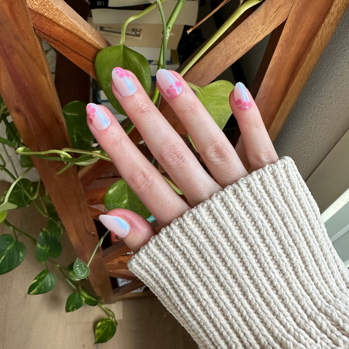 Fuchsia Florals - Press-On | Short | Almond showing hand with short almond iridescent press-on nails and pink floral accents indoors