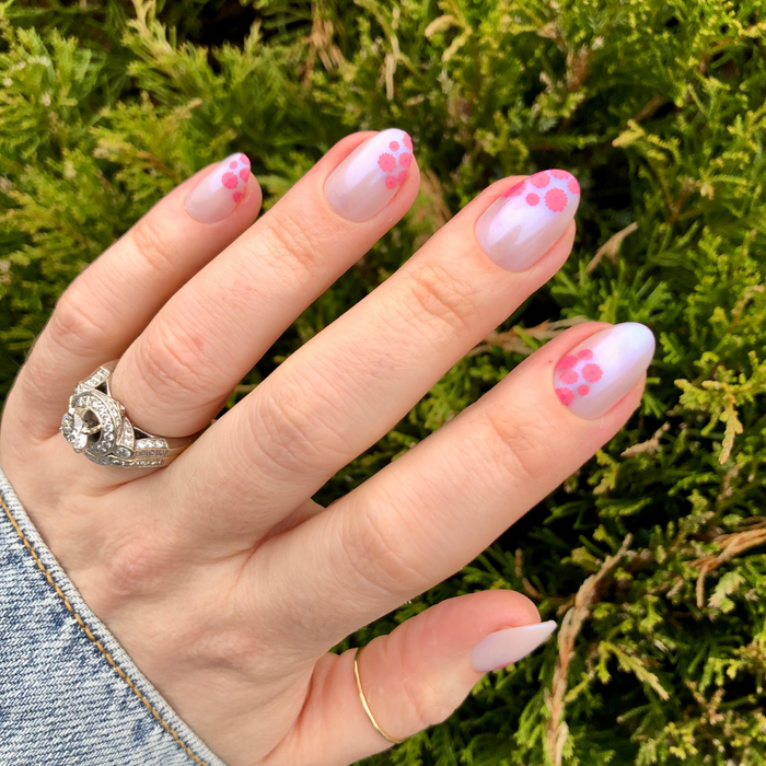 Fuchsia Florals - Press-On | Short | Almond showing hand with short almond iridescent press-on nails with pink floral accents outdoors