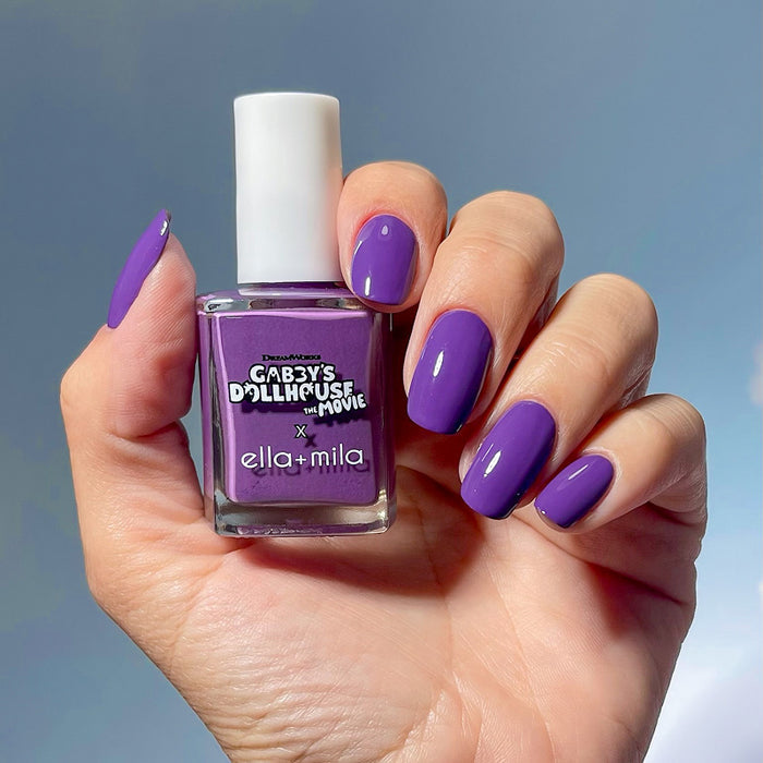 Gabby's Dollhouse Carlita's Violet Vroom purple nail polish manicure on a medium skin tone, holding the bottle
