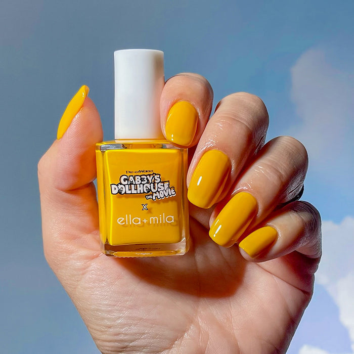 Gabby's Dollhouse Pillow Cat Sunshine yellow nail polish manicure on a medium skin tone, holding the bottle