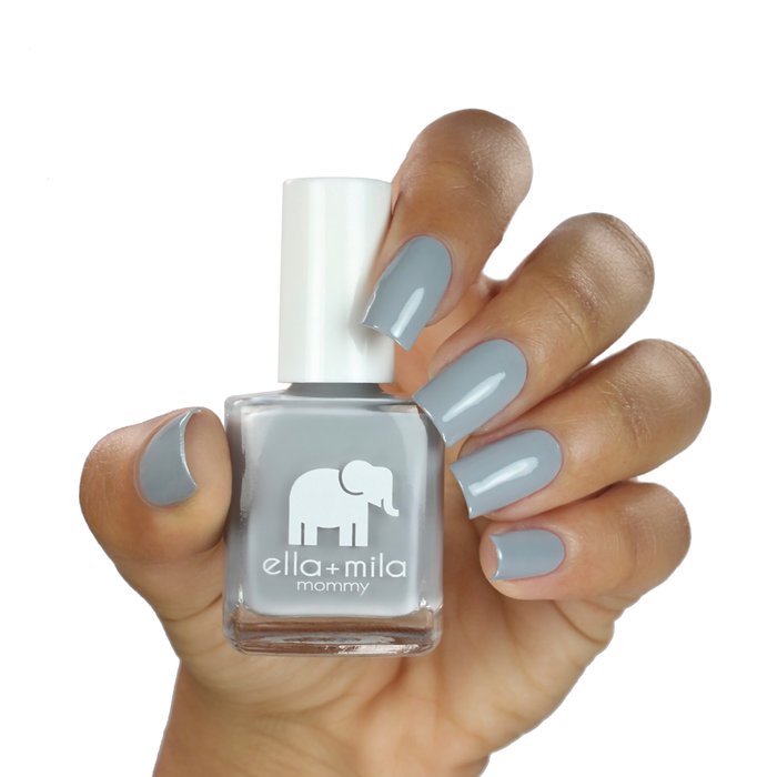 Grey Skies cement grey nail polish on a medium skin tone, hand holding the bottle