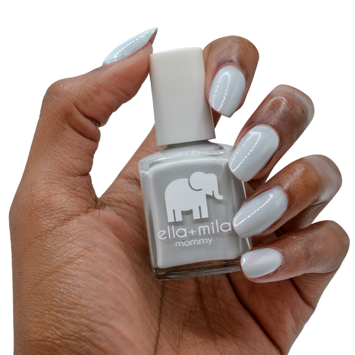 Grey Skies cool grey nail polish on a deep skin tone, hand holding the bottle