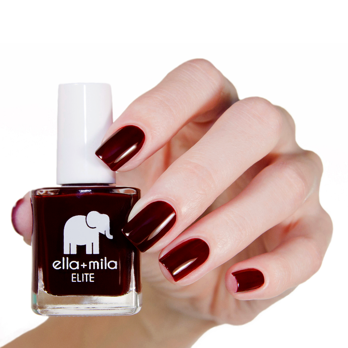 Holiday Fling dark burgundy nail polish manicure on a light skin tone with the bottle