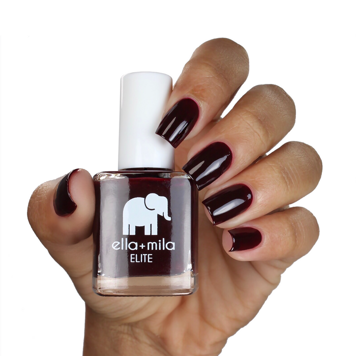Holiday Fling brown burgundy nail polish on a medium skin tone, hand holding the bottle