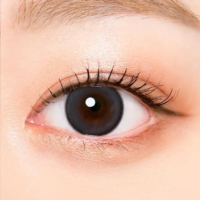 Macro shot of an eye wearing the i-Sha Oriana Mune 1-Day Grey (10pk) prescription colour contact lens, showing the multi-colored detail and natural effect on dark brown eyes.