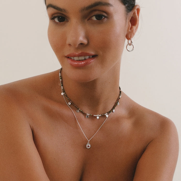 Woman wearing a necklace and earrings on a plain background