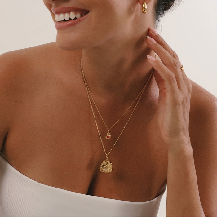 Woman wearing gold necklaces and earrings, smiling.