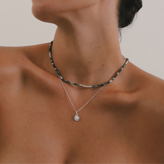 Necklace with a pendant on a person against a neutral background