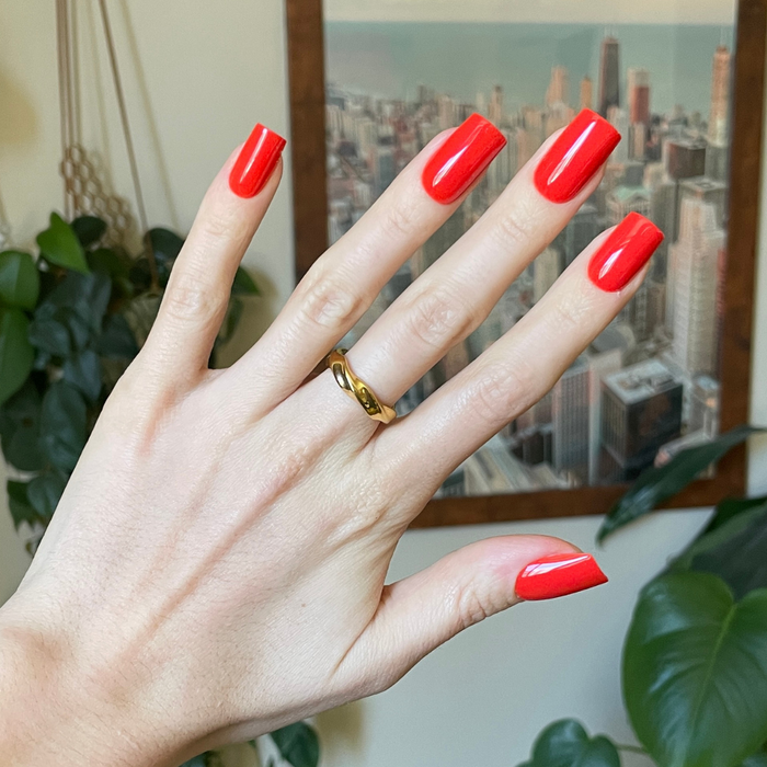 Lava - Press-On | Medium | Square showing hand with shiny bright spicy orange-red medium square false nails on indoor background