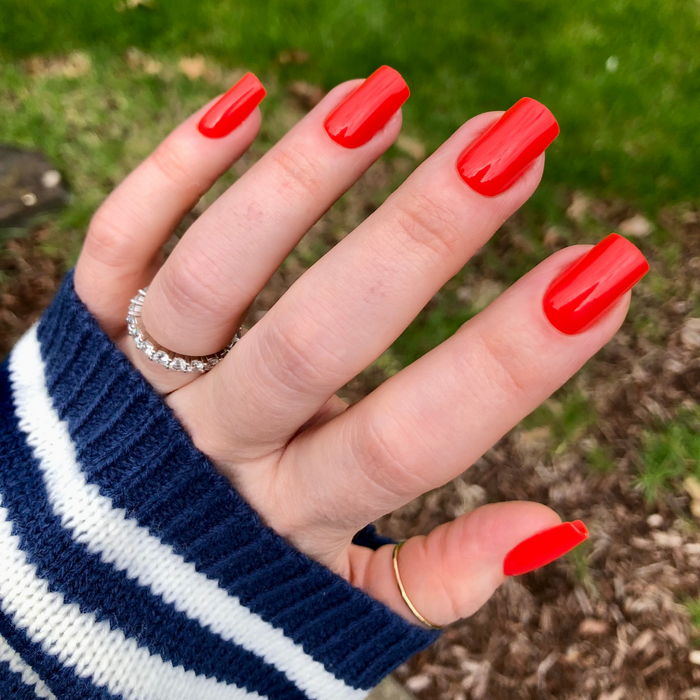 Lava - Press-On | Medium | Square showing hand with glossy bright spicy orange red medium square false nails outdoors